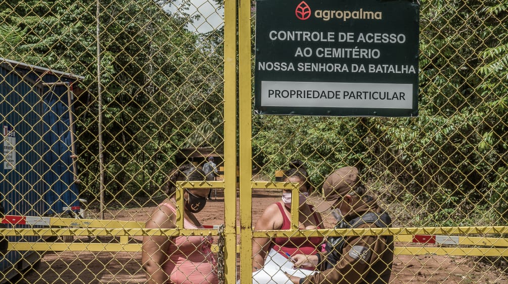 Due donne controllate da una guardia dietro un cancello sbarrato - Testo scritto sul cartello dell'azienda: Agropalma - Controllo dell'accesso al cimitero di Nossa Senhora da Batalha. PROPRIETÀ PRIVATA