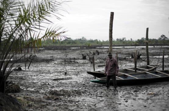 Un uomo si trova nel letto di un fiume inquinato dal petrolio nel Delta del Niger.