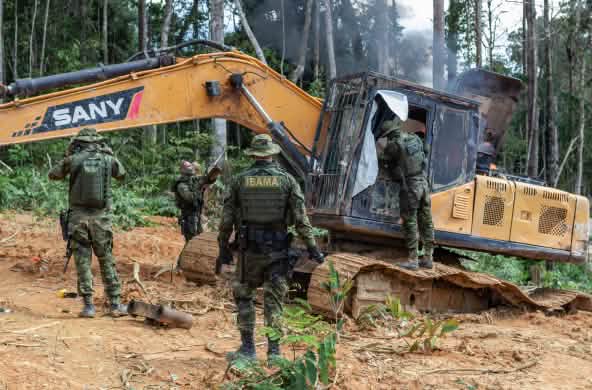 Intervento dell'agenzia ambientale IBAMA. Un gruppo di uomini in tenuta militare interviene su una draga gialla nella foresta pluviale.