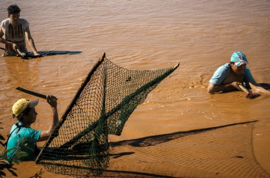 Tre persone pescano con reti tradizionali sul fiume Pilcomayo, in Paraguay.