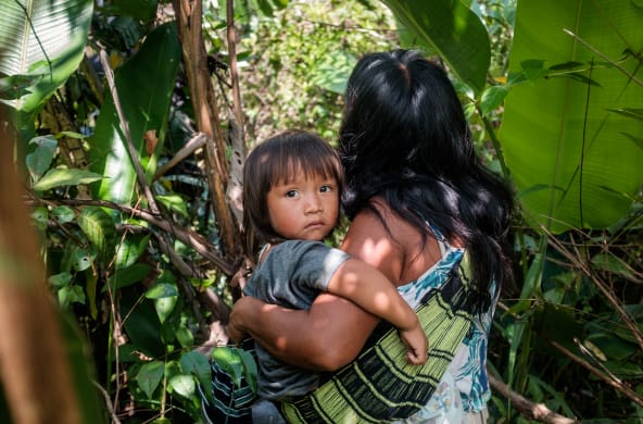 Donna indigena Ka'apor nella vegetazione della foresta amazzonica con il suo bambino in braccio.