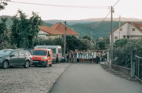I partecipanti all'accampamento Barroso senza miniere a Covas do Barroso, in Portogallo, manifestano per le strade del villaggio con uno striscione che recita “Barroso vive e resiste”.