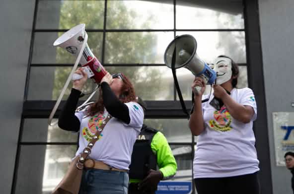 Due membri del collettivo ecuadoriano YASunidos protestano con i megafoni davanti alla sede del Tribunale Contenzioso Elettorale (TCE)