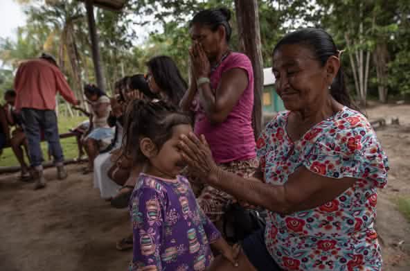 Una bambina annusa gli oli essenziali versati sulla mano di una donna indigena.