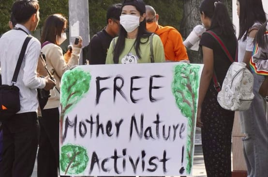 Giovane donna con un grande cartello con la scritta “Liberate gli attivisti di Mother Nature!”