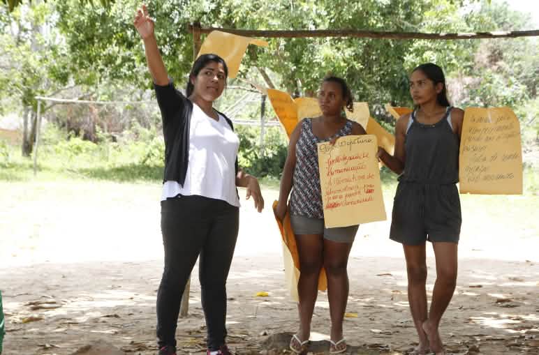 Tre partecipanti a un laboratorio del Movimento Xingu Vivo para Sempre tengono in mano dei cartelli.