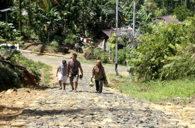 Tre persone su una strada asfaltata in un villaggio nella foresta