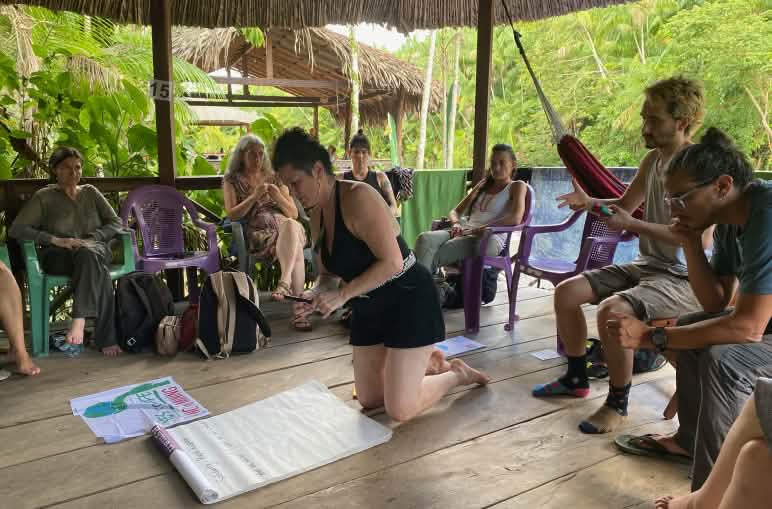 Gruppo di otto persone durante una riunione in una capanna di legno aperta nella foresta tropicale