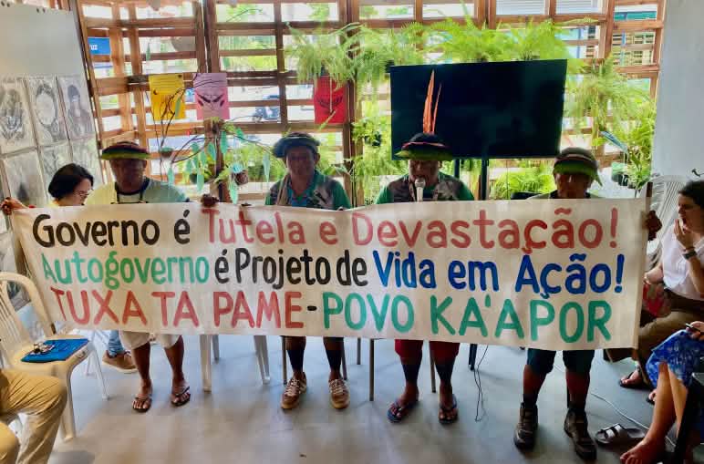 Quattro indigeni Kaápor sventolano uno striscione in una sala riunioni