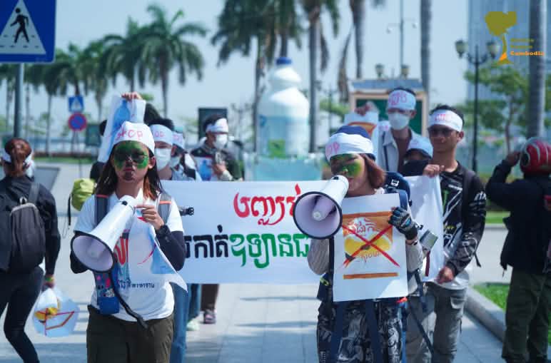 Un gruppo di giovani studenti attraversa una strada con megafoni e cartelli.