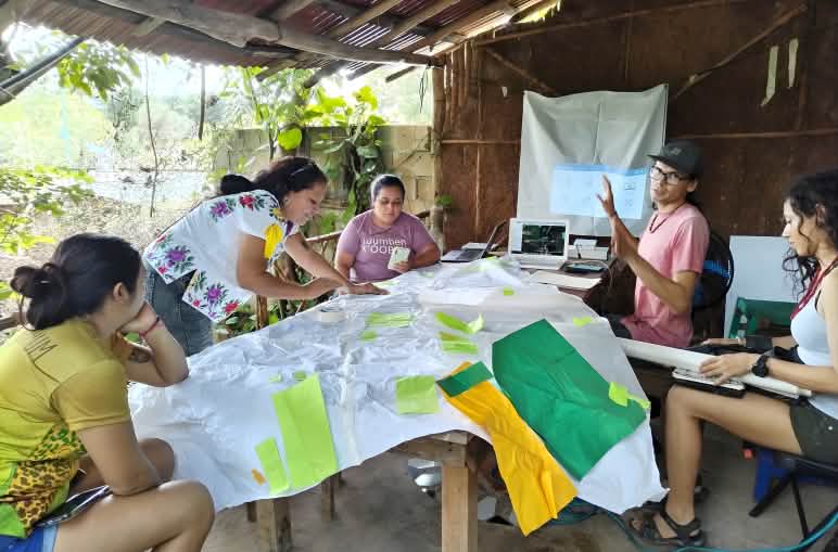 Donne lavorano attorno a un tavolo in attività di conservazione, mappatura e pianificazione