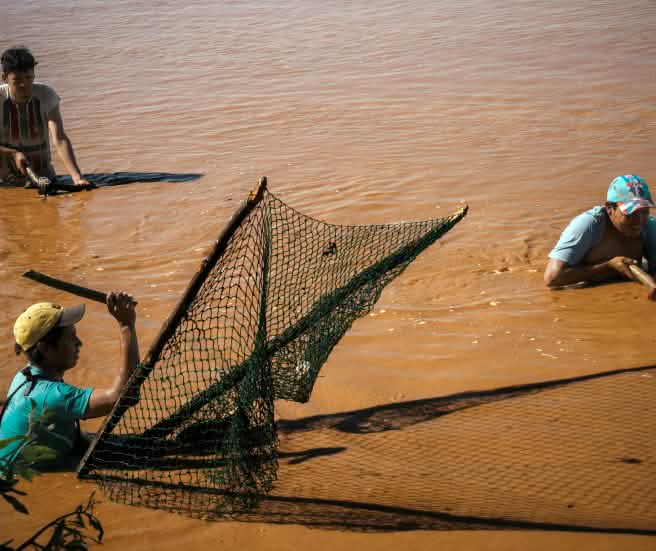 Tre persone pescano con reti tradizionali sul fiume Pilcomayo, in Paraguay.