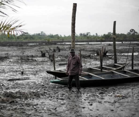 Un uomo si trova nel letto di un fiume inquinato dal petrolio nel Delta del Niger.