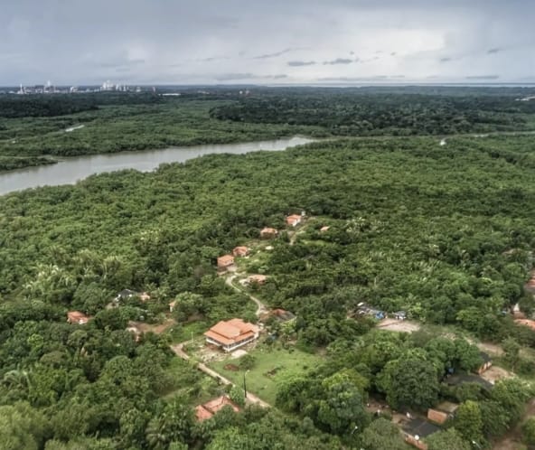 Vista aerea delle case immerse nella rigogliosa vegetazione amazzonica e, sullo sfondo, un fiume con mangrovie sulle rive a Tauá Mirim, Maranhao, Brasile