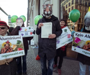 I manifestanti con maschere di animali tengono in mano dei cartelli.