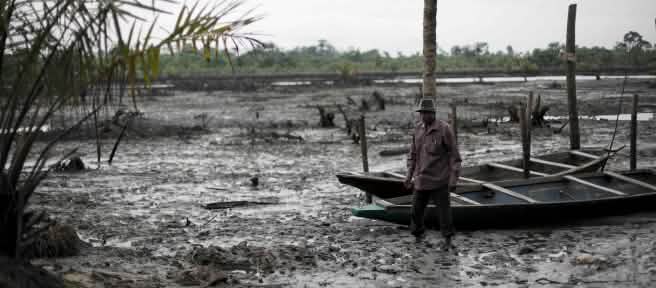 Un uomo si trova nel letto di un fiume inquinato dal petrolio nel Delta del Niger.