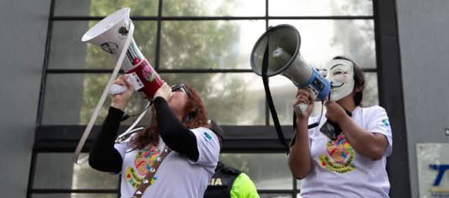 Due membri del collettivo ecuadoriano YASunidos protestano con i megafoni davanti alla sede del Tribunale Contenzioso Elettorale (TCE)