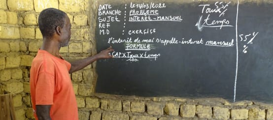 Lezioni nel villaggio di Bekombo: l'insegnante spiega il calcolo dell'interesse mensile (© Bonobo Alive) Insegnante in una scuola di villaggio nella Repubblica Democratica del Congo
