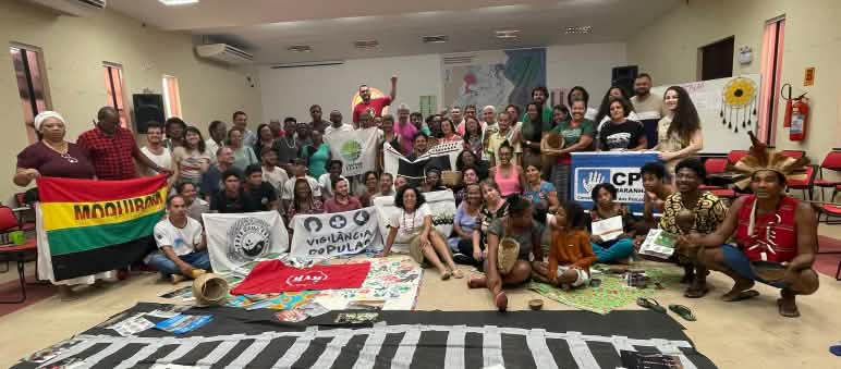 Foto di gruppo di circa 50 persone con striscioni in una sala riunioni.