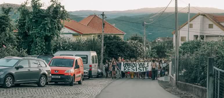 I partecipanti all'accampamento Barroso senza miniere a Covas do Barroso, in Portogallo, manifestano per le strade del villaggio con uno striscione che recita “Barroso vive e resiste”.