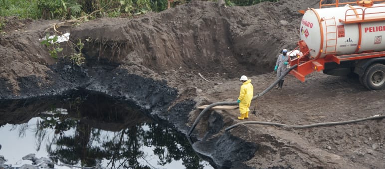 Due lavoratori del settore petrolifero pompano il petrolio greggio da un pozzo di terra in un'autocisterna.