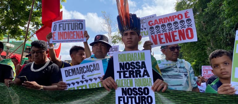 Marcia dei popoli indigeni per la foresta pluviale durante il vertice sull'Amazzonia a Belém Indigeni che marciano in fila reggendo cartelli con slogan come: “La nostra terra è il nostro futuro”