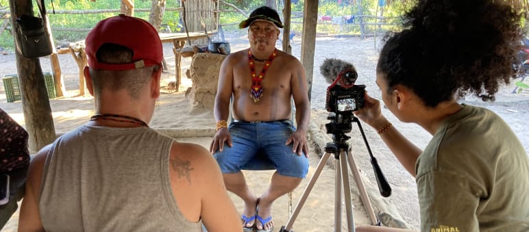 Due giornalisti di The Intercept di spalle durante l'intervista video con il leader indigeno Itahu Ka'apor, che si trova di fronte.