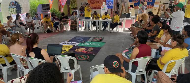 Una trentina di persone sedute su sedie formano un cerchio in una sala riunioni