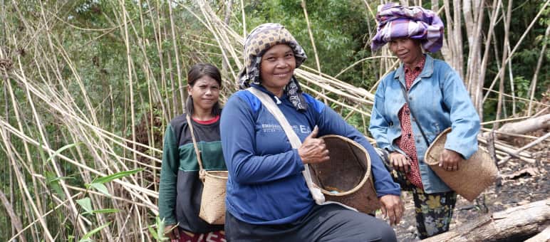 Tre donne Dayak con cesti da raccolta sorridono alla macchina fotografica.