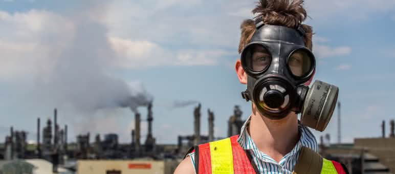 Un uomo protesta con una maschera antigas contro l'estrazione delle sabbie bituminose in Canada.