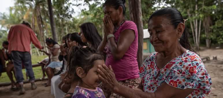Una bambina annusa gli oli essenziali versati sulla mano di una donna indigena.