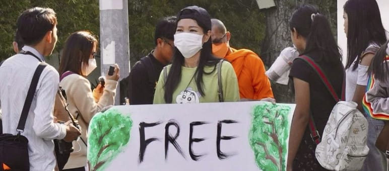 Giovane donna con un grande cartello con la scritta “Liberate gli attivisti di Mother Nature!”