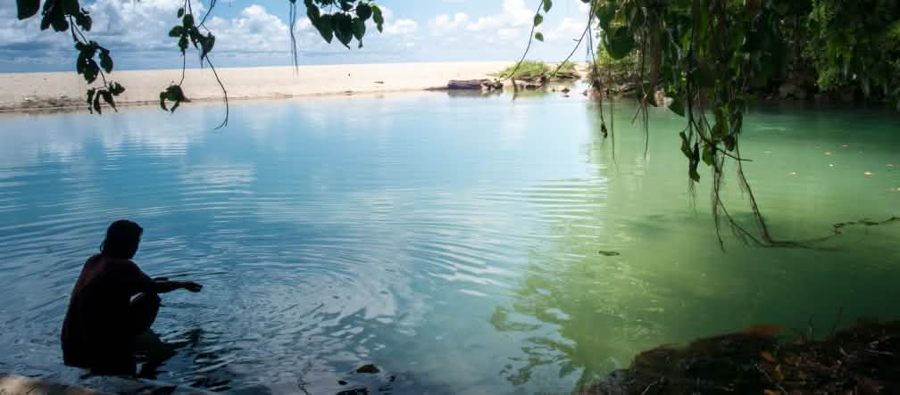 L'isola di Celebes ha 6.000 chilometri di costa con spiagge sabbiose Una donna in una baia circondata da acqua, rocce e sabbia