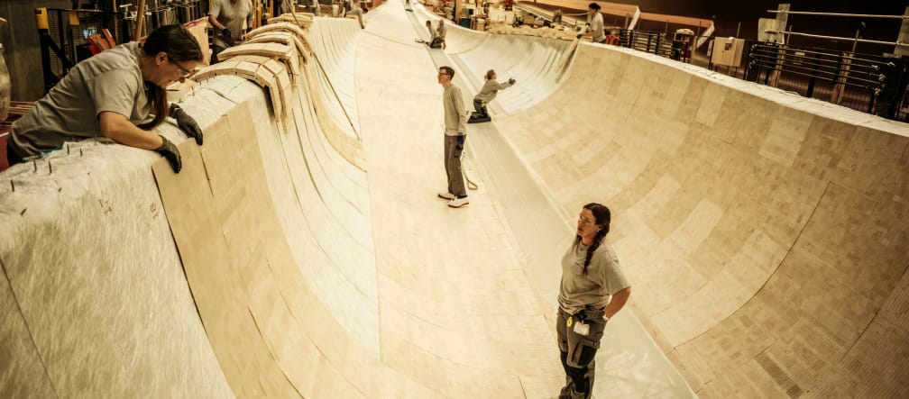 Diverse persone si trovano all'interno del rivestimento in legno di balsa per la costruzione della pala di un rotore.