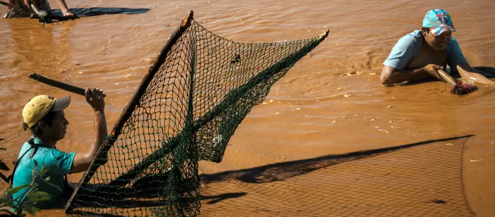 Tre persone pescano con reti tradizionali sul fiume Pilcomayo, in Paraguay.