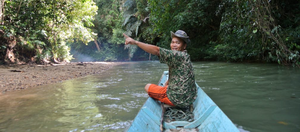 Un uomo su una barca indica la foresta pluviale di Sarawak, nel Borneo.