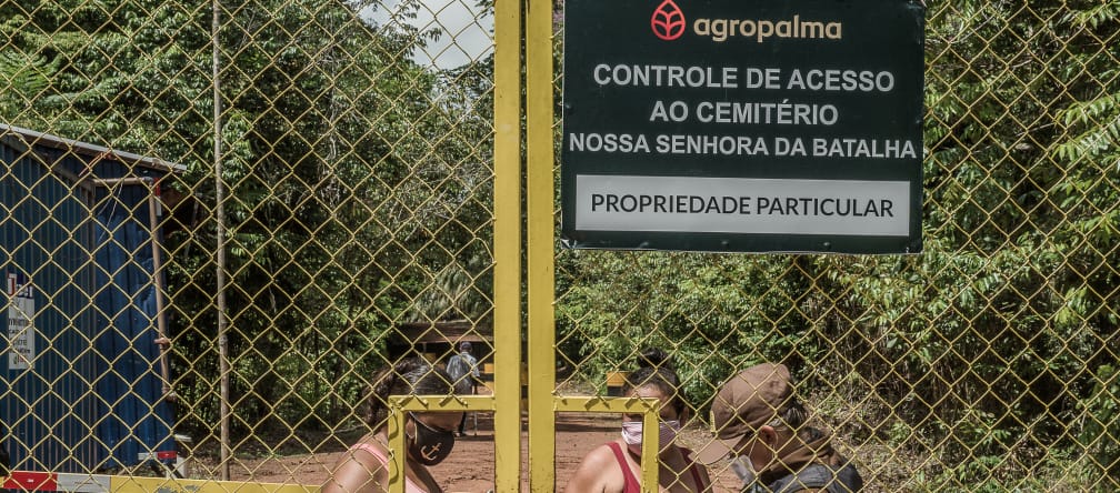 Due donne controllate da una guardia dietro un cancello sbarrato - Testo scritto sul cartello dell'azienda: Agropalma - Controllo dell'accesso al cimitero di Nossa Senhora da Batalha. PROPRIETÀ PRIVATA