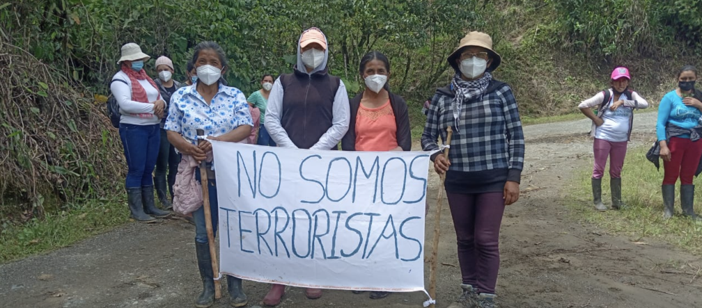 Donne accusate di terrorismo per aver difeso la vita e la natura dalle miniere protestano con un cartello "Non siamo terroriste".