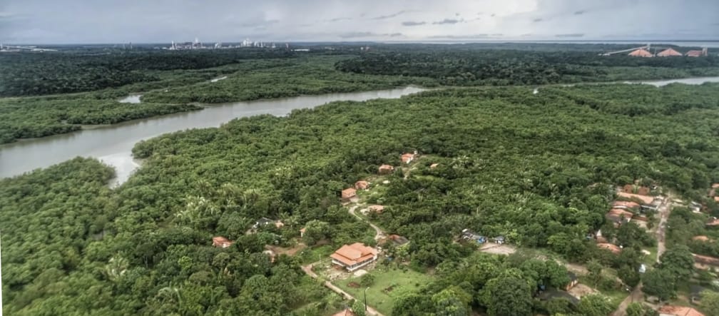 Vista aerea delle case immerse nella rigogliosa vegetazione amazzonica e, sullo sfondo, un fiume con mangrovie sulle rive a Tauá Mirim, Maranhao, Brasile