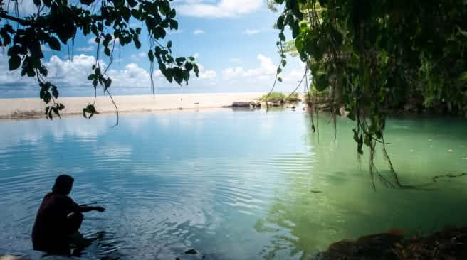 L'isola di Celebes ha 6.000 chilometri di costa con spiagge sabbiose Una donna in una baia circondata da acqua, rocce e sabbia