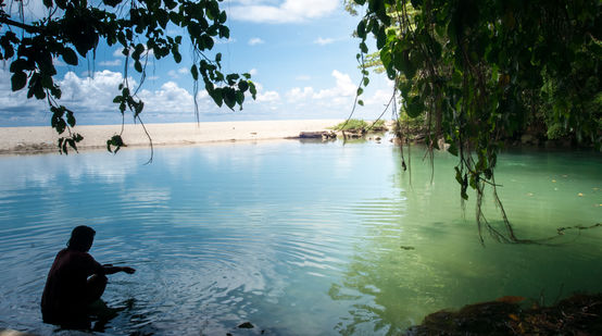 Una donna in una baia circondata da acqua, rocce e sabbia