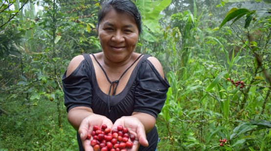 Una donna indigena nella foresta mostra dei frutti rossi