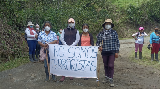 Donne accusate di terrorismo per aver difeso la vita e la natura dalle miniere protestano con un cartello "Non siamo terroriste".