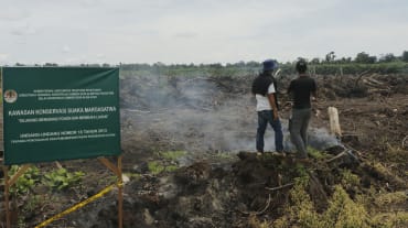 Due uomini su una radura e il cartello “Riserva della fauna selvatica”