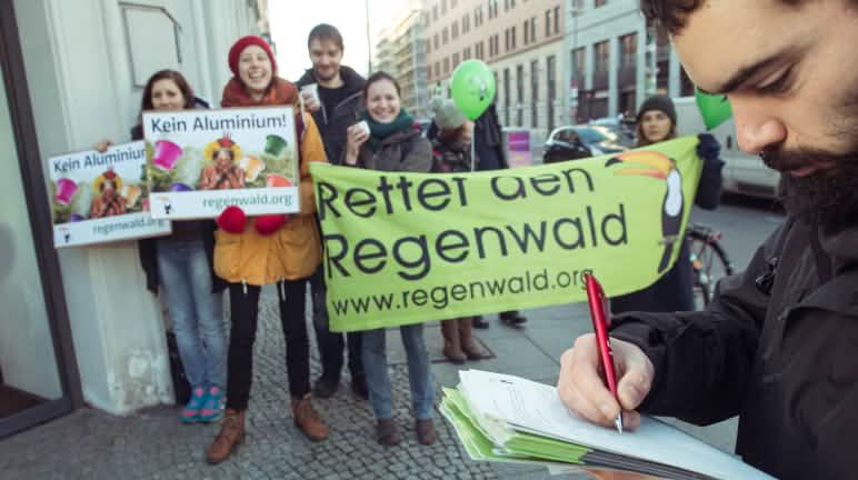 Difendere chi difende, porre fine alle cause intimidatorie Attivisti di Salviamo la Foresta/Rettet den Regenwald manifestano con alcuni striscioni