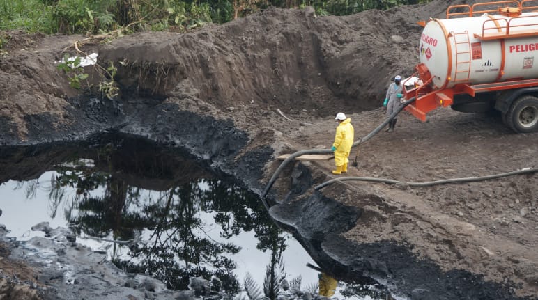 Due lavoratori del settore petrolifero pompano il petrolio greggio da un pozzo di terra in un'autocisterna.