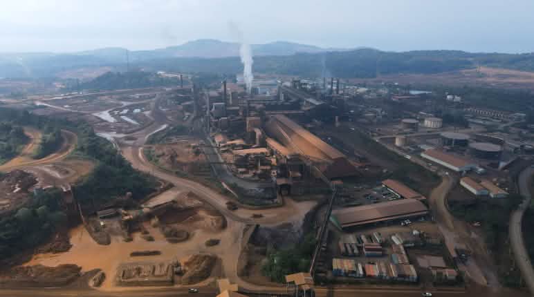 Zona industriale speciale di Gunbuster, una natura selvaggia dopo la deforestazione Fonderia di nichel e infrastrutture viste dall'alto, con il mare sullo sfondo.