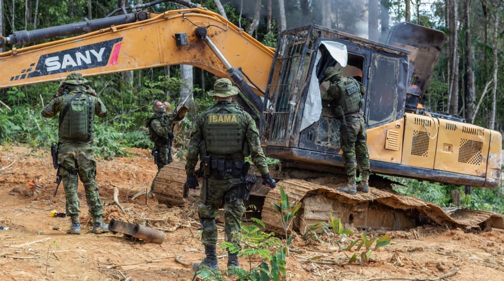 Intervento dell'agenzia ambientale IBAMA. Un gruppo di uomini in tenuta militare interviene su una draga gialla nella foresta pluviale.