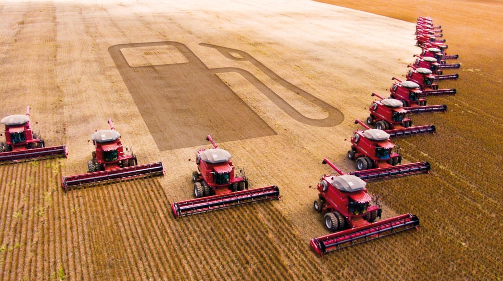 Fotomontaggio: macchinari per la mietitura in una piantagione di soia. La sagoma di una pompa di benzina è visibile nell'area raccolta. Fotomontaggio: Fotomontaggio: 15 mietitrebbie al lavoro in un campo di soia lasciano una scia a forma di pompa di benzina