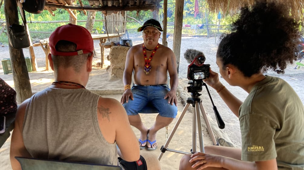Due giornalisti di The Intercept di spalle durante l'intervista video con il leader indigeno Itahu Ka'apor, che si trova di fronte.